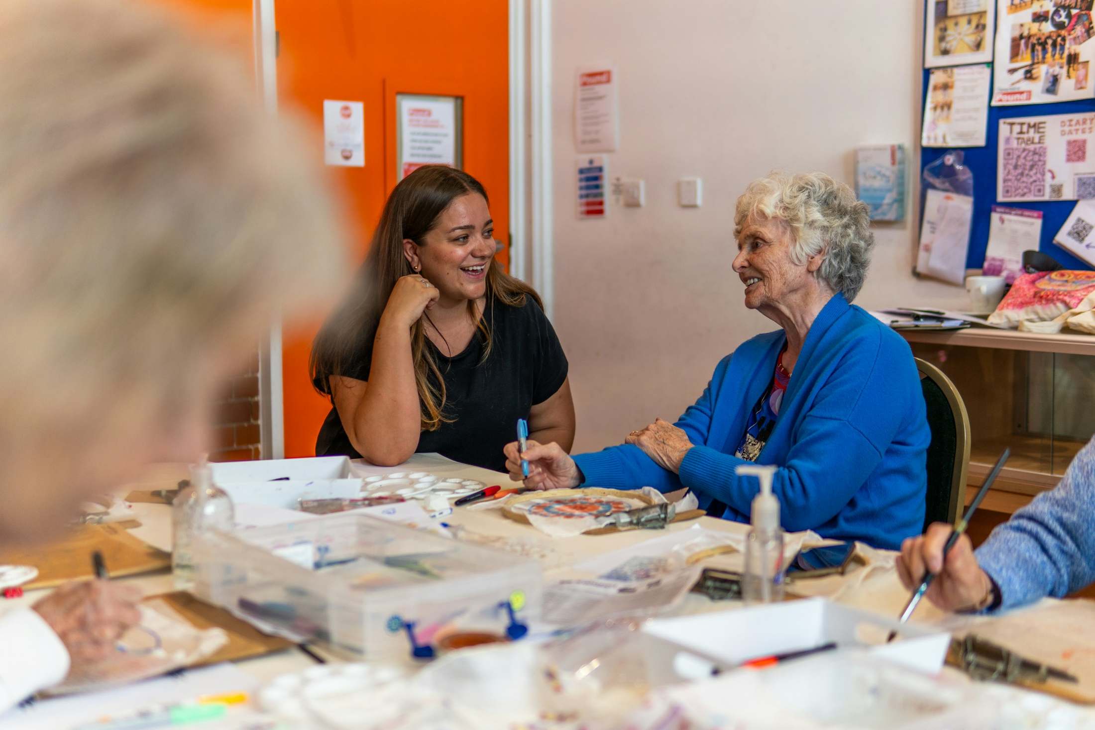 Two women laugh together across a table.