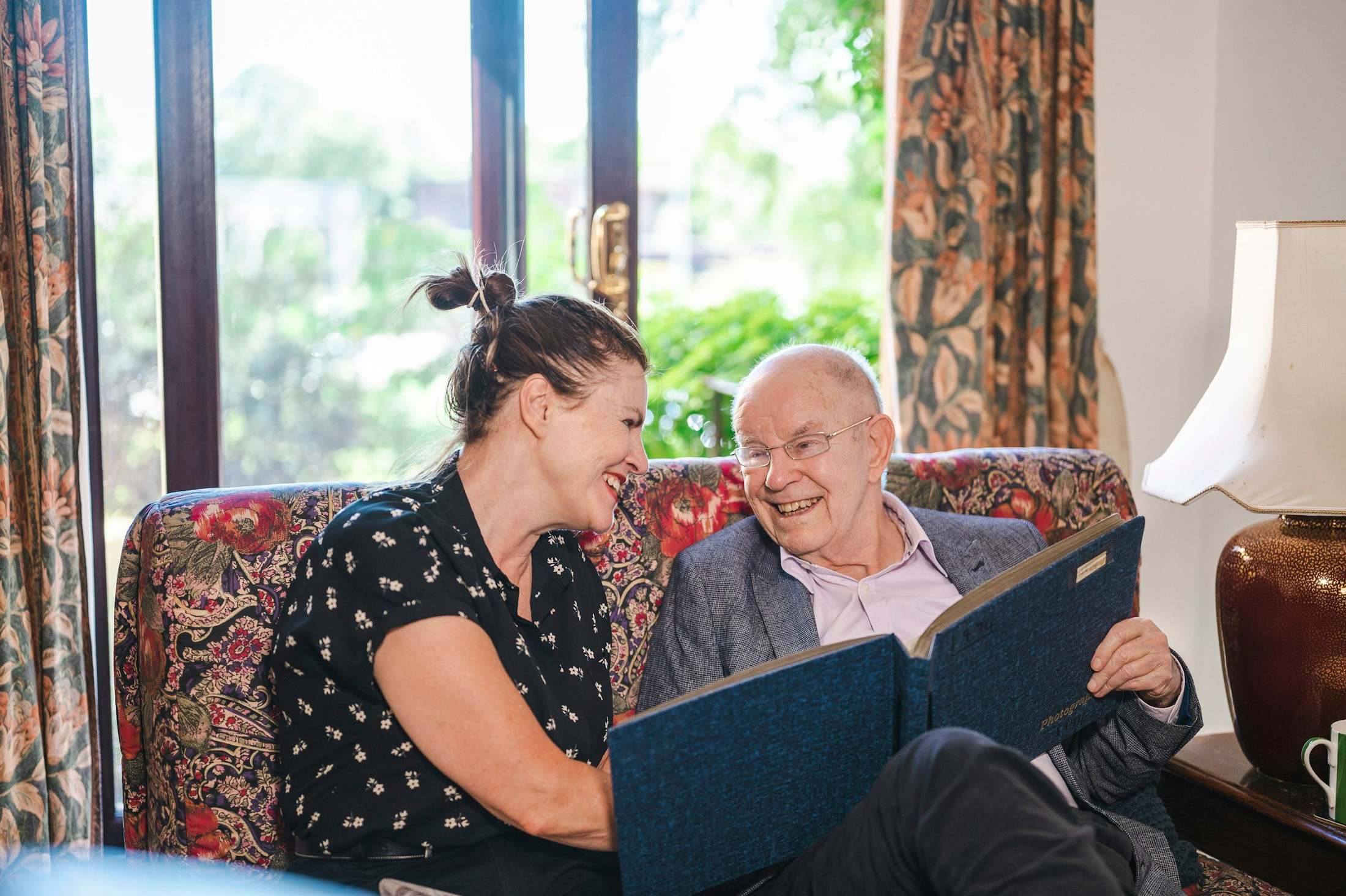 A younger woman and an older man look through a photo album together.