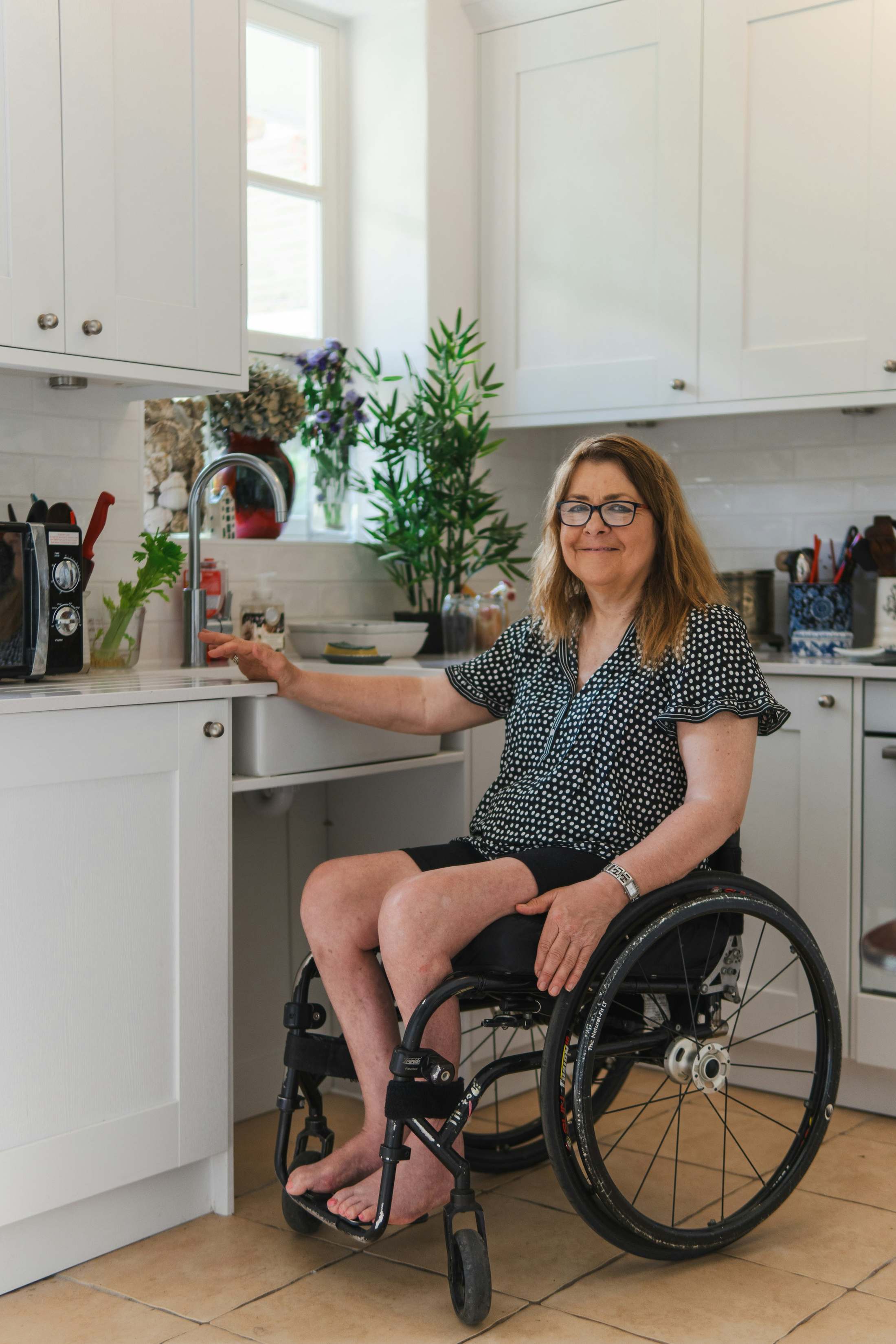 A woman in a wheelchair uses an accessible kitchen sink.